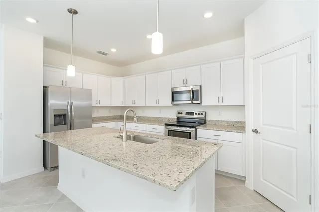 a kitchen with stainless steel appliances granite countertop a sink a stove and a refrigerator