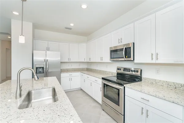 a kitchen with granite countertop a sink a stove and microwave
