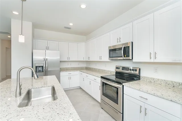 a kitchen with granite countertop a sink a stove and microwave