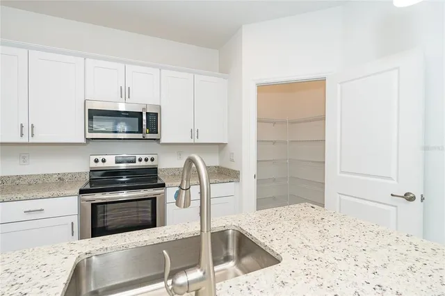 a kitchen with granite countertop a stove a sink and a microwave