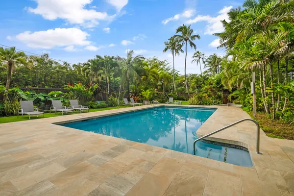 a view of a swimming pool with a bench and trees