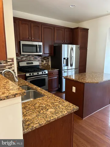 a large kitchen with stainless steel appliances and wooden cabinets