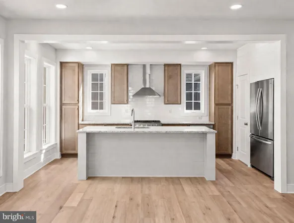 a kitchen with kitchen island wooden floor and refrigerator