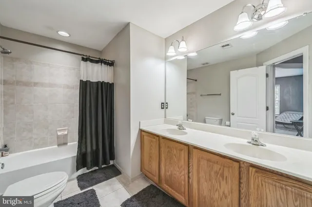 a bathroom with a double vanity sink toilet mirror and bathtub