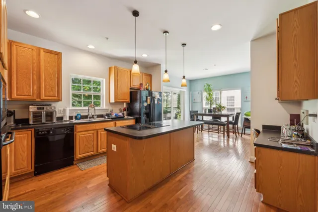 a kitchen with stainless steel appliances granite countertop wooden floors a stove a sink and a window