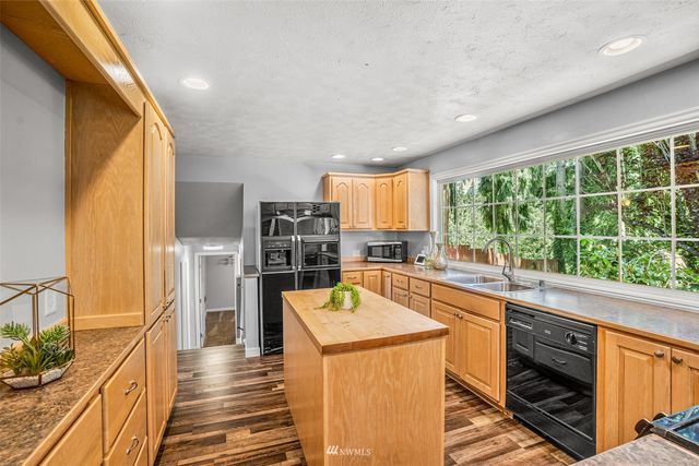 a kitchen with stainless steel appliances a stove top oven a sink a refrigerator white cabinets and wooden floor