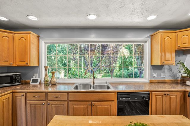 a kitchen with stainless steel appliances wooden cabinets a sink and a large window