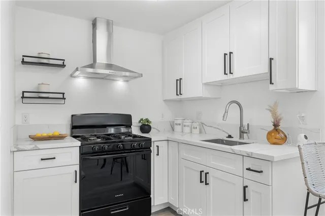 a kitchen with stainless steel appliances a stove a sink and a white cabinets