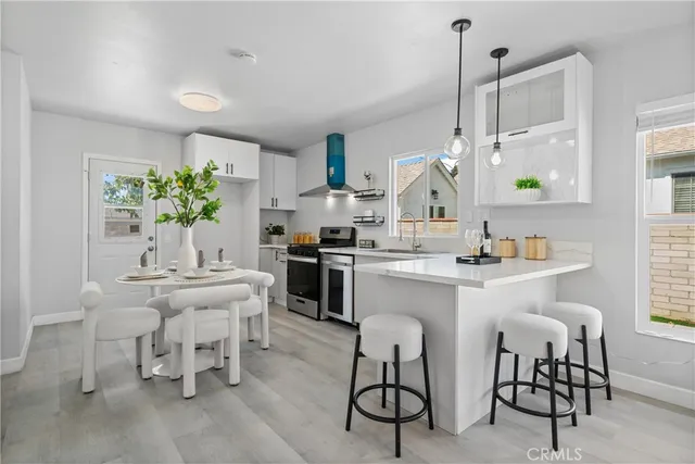 a kitchen with a dining table chairs sink and white cabinets