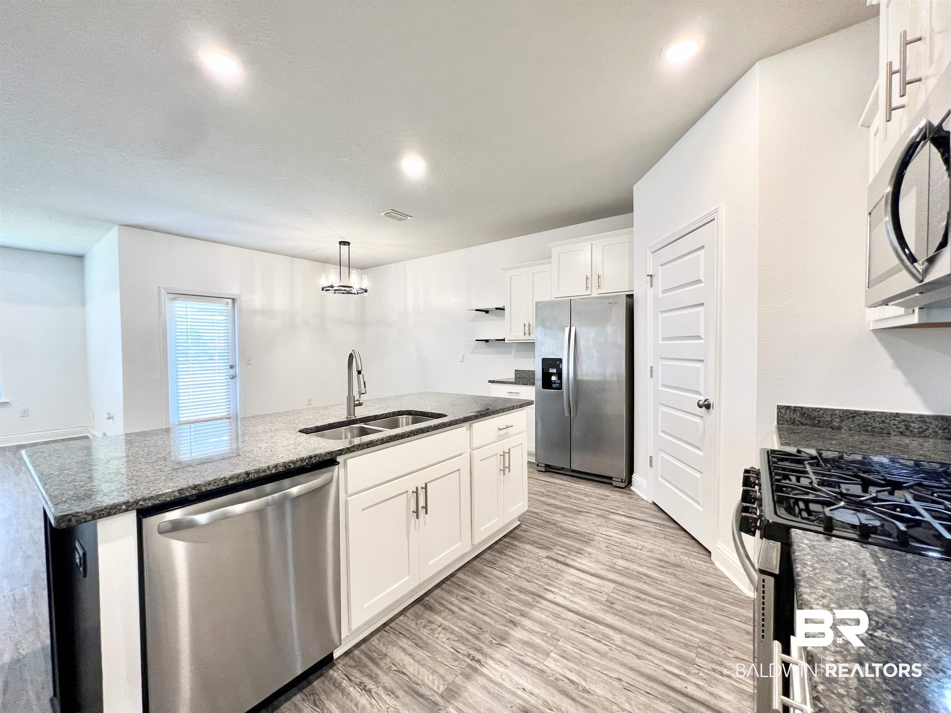 24785 Slater Mill Road Daphne, AL 36526 - Photo 4 of 46 Kitchen featuring sink, white cabinetry, stainless steel appliances, and an island with sink