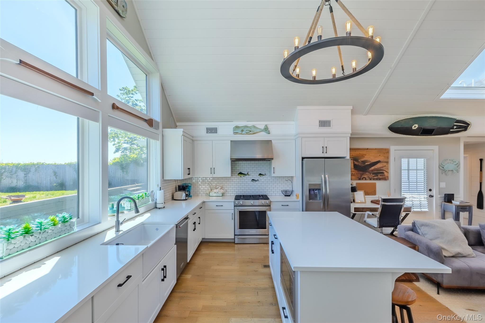 53 Old Neck Road South Center Moriches, NY 11934 - Photo 23 of 50 Kitchen featuring appliances with stainless steel finishes, wall chimney exhaust hood, a chandelier, a sink, and plenty of natural light