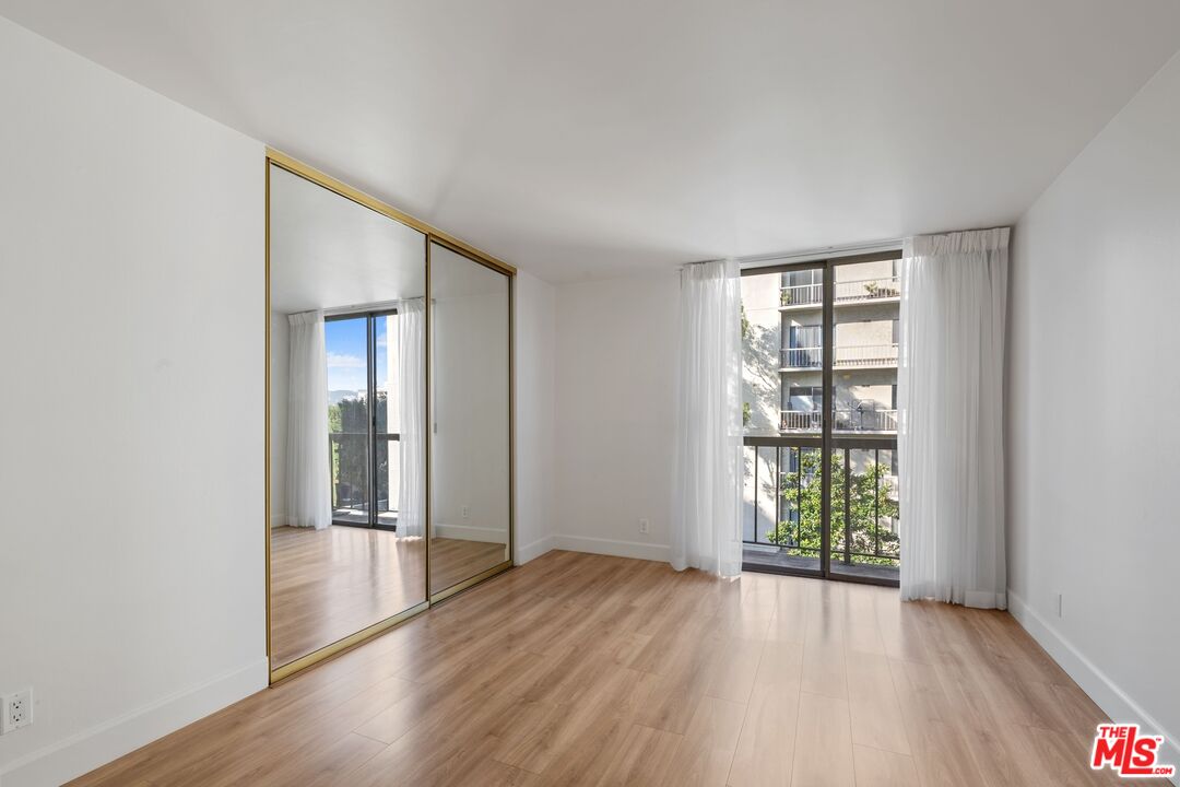 10747 Wilshire Boulevard, Unit 701 Los Angeles, CA 90024 - Photo 6 of 14 an empty room with wooden floor and windows