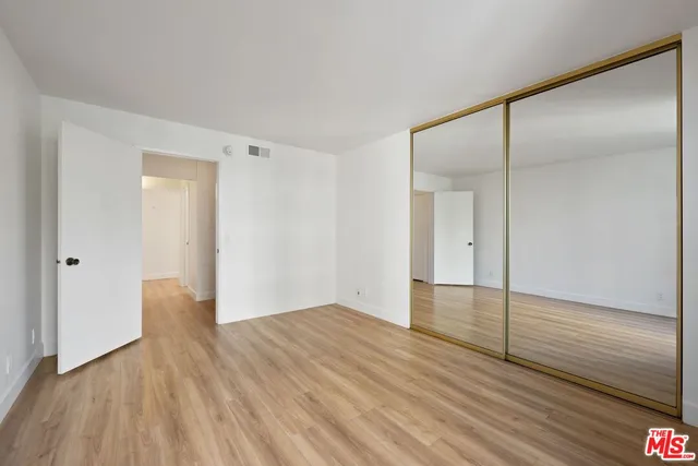 a view of an empty room with wooden floor and a bathroom