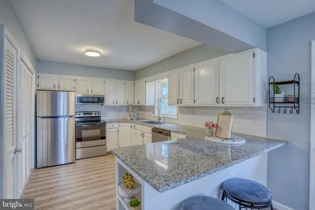 a kitchen with stainless steel appliances granite countertop a sink refrigerator and cabinets