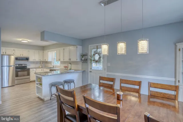 a kitchen with stainless steel appliances granite countertop a kitchen island hardwood floor sink stove dining table and chairs