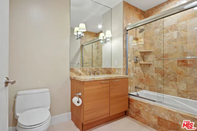 a bathroom with a granite countertop sink a toilet a mirror and shower