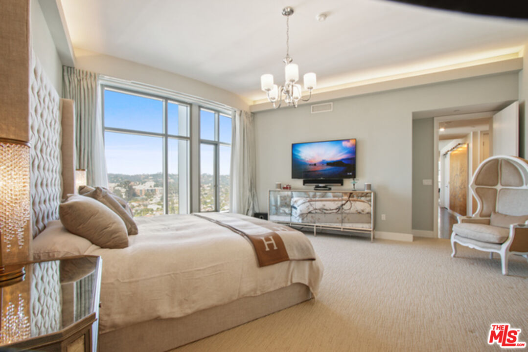 10776 Wilshire Boulevard, Unit 1801 Los Angeles, CA 90024 - Photo 8 of 15 a bedroom with a bed and a chandelier