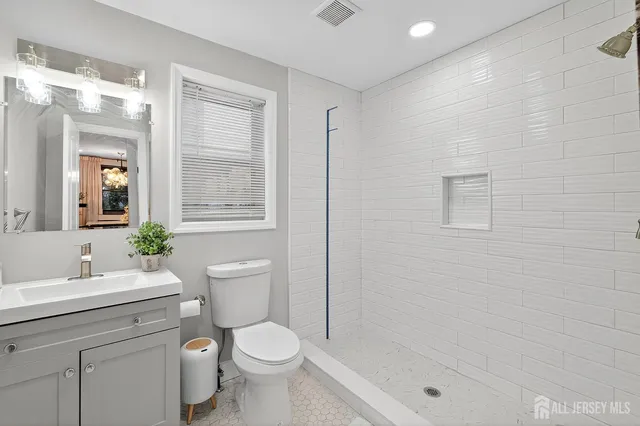 a bathroom with a granite countertop toilet a sink a mirror and shower