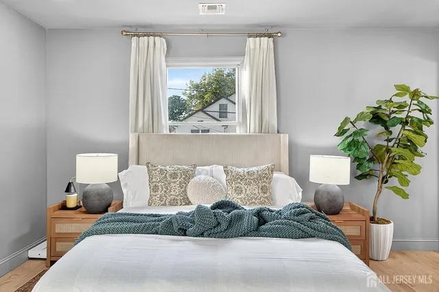 a bed sitting in a bedroom next to a window with potted plant