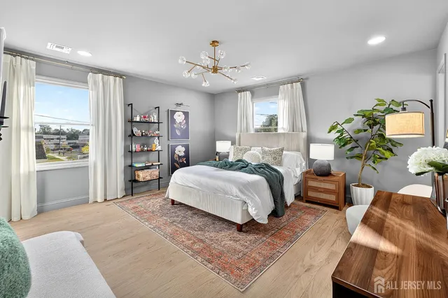 a spacious bedroom with a large bed chandelier and a window