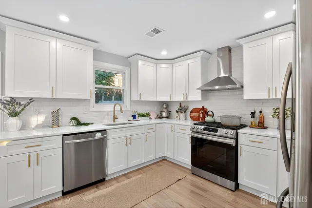 a kitchen with white cabinets stainless steel appliances and sink