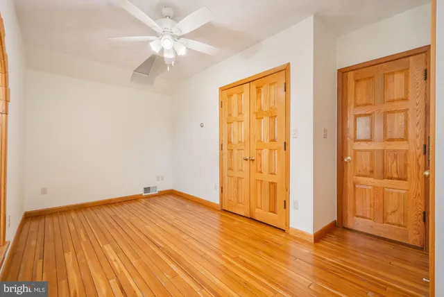 an empty room with wooden floor and a ceiling fan