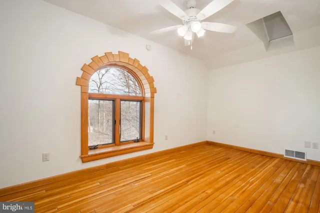 an empty room with a window and ceiling fan