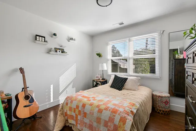 a bedroom with a bed and dresser with wooden floor