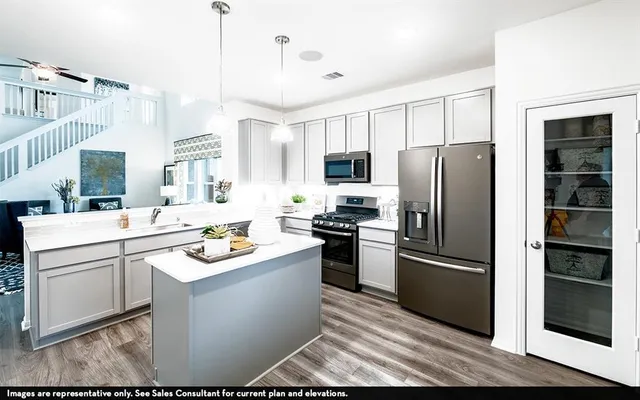 a kitchen with stainless steel appliances kitchen island a refrigerator sink and cabinets