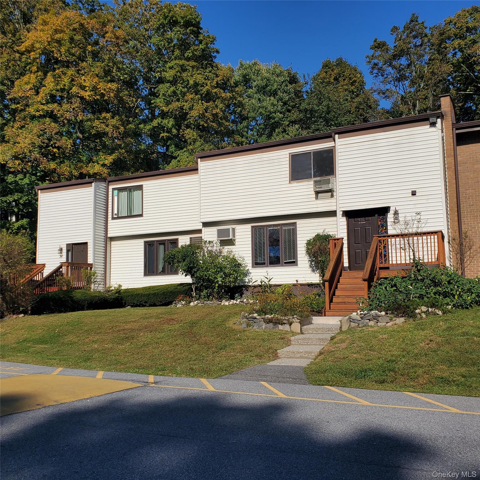 Colonial home featuring a front lawn and view of wooded area