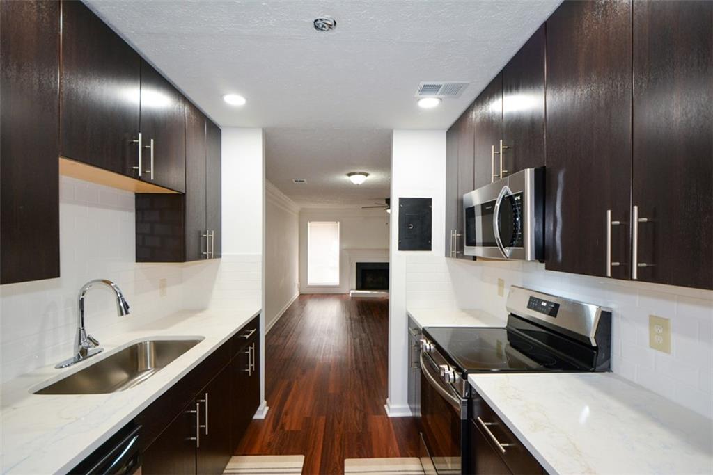 2340 Beaver Ruin Road, Unit UN26 Norcross, GA 30071 - Photo 19 of 42 a large kitchen with granite countertop a sink and a stove top oven