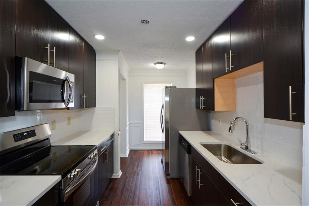 2340 Beaver Ruin Road, Unit UN26 Norcross, GA 30071 - Photo 22 of 42 a kitchen with granite countertop stainless steel appliances cabinets a sink and a wooden floor