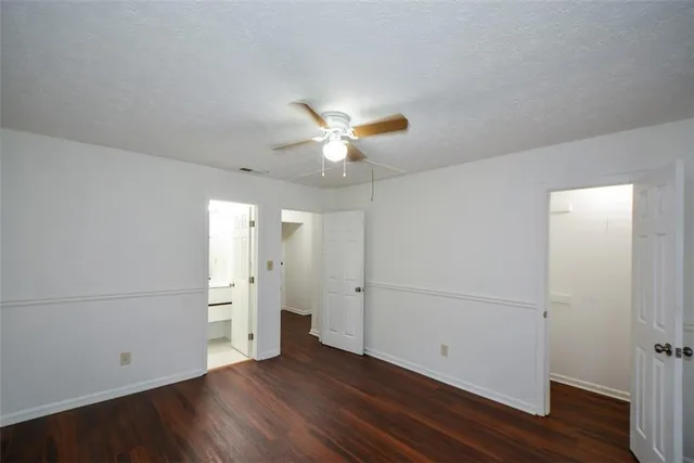 an empty room with wooden floor and a ceiling fan