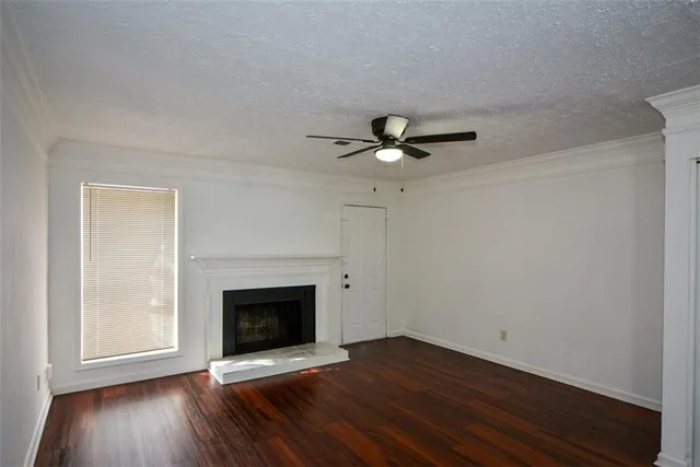 a view of an empty room with wooden floor fireplace and a window