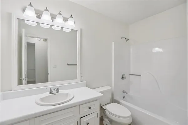 an empty room with a chandelier fan and windows