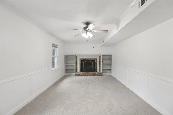 a view of an empty room with chandelier fan