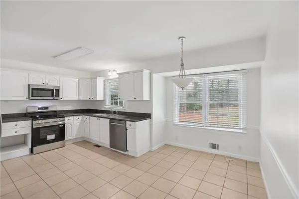 a kitchen with stainless steel appliances granite countertop a refrigerator a stove a sink dishwasher and white cabinets with wooden floor