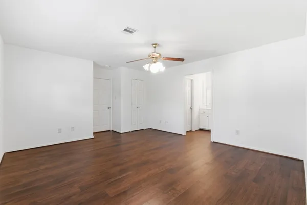 an empty room with wooden floor and ceiling fan