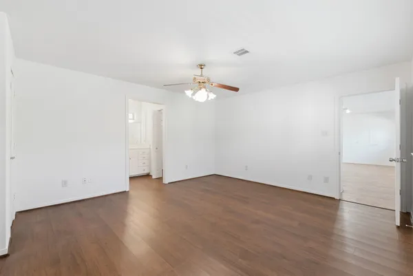 an empty room with wooden floor and ceiling fan