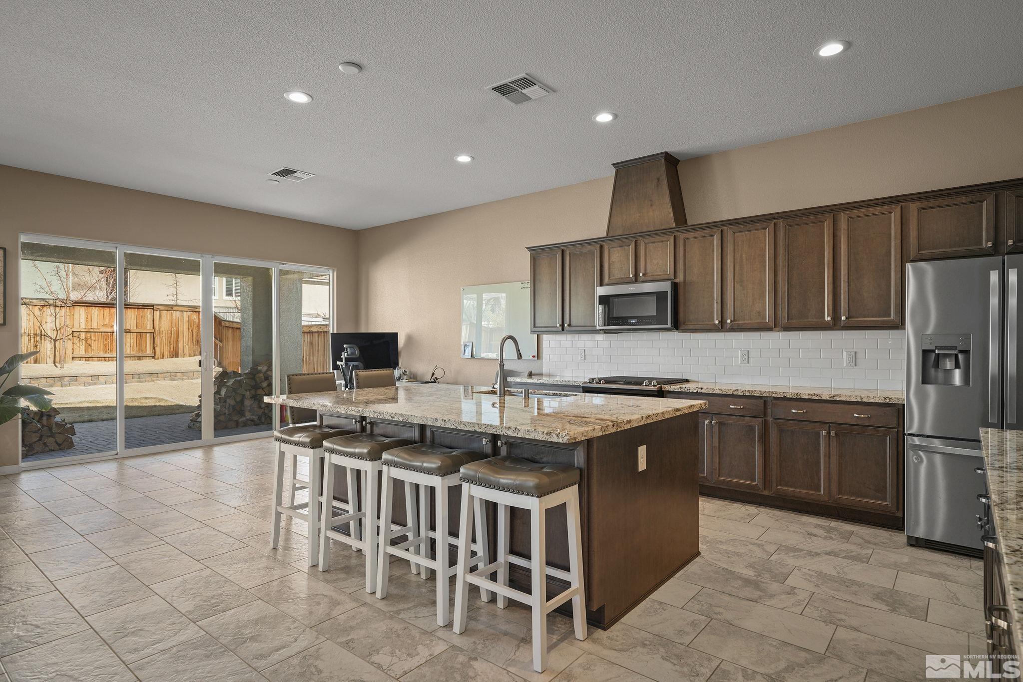 2895 Ethelinda Way Reno, NV 89521 - Photo 8 of 30 a kitchen with stainless steel appliances granite countertop a stove top oven a sink dishwasher a dining table and chairs with wooden cabinets