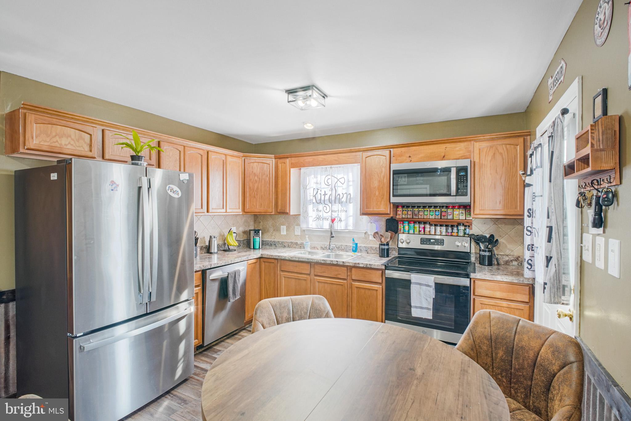 12254 Birkdale Road Ruther Glen, VA 22546 - Photo 8 of 68 a kitchen with stainless steel appliances granite countertop a refrigerator a stove a sink dishwasher a dining table and chairs with wooden floor