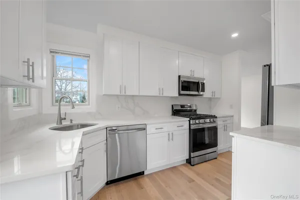 a kitchen with granite countertop white cabinets and stainless steel appliances