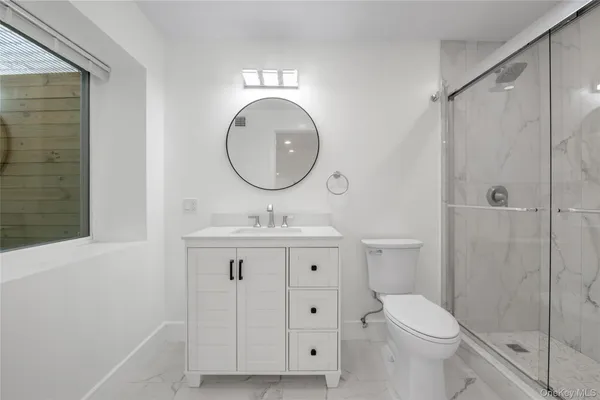 a bathroom with a toilet a sink a mirror and a shower