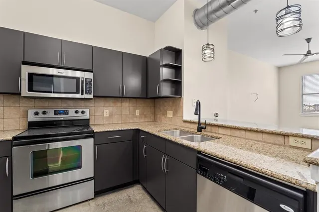 a kitchen with granite countertop a sink cabinets and stainless steel appliances