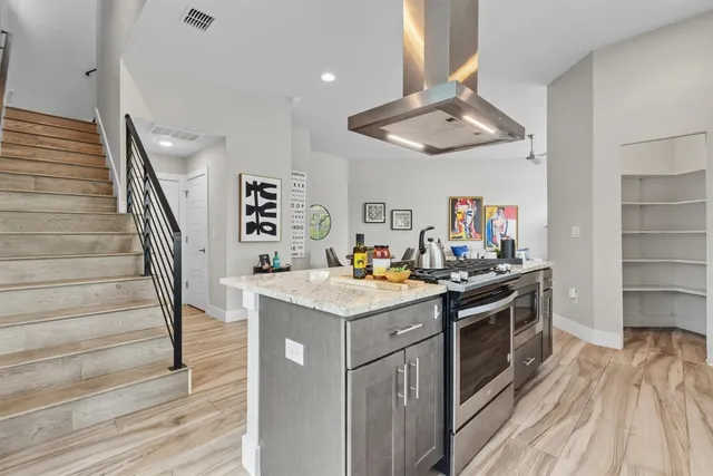 a kitchen with stainless steel appliances granite countertop a stove and a view of living room