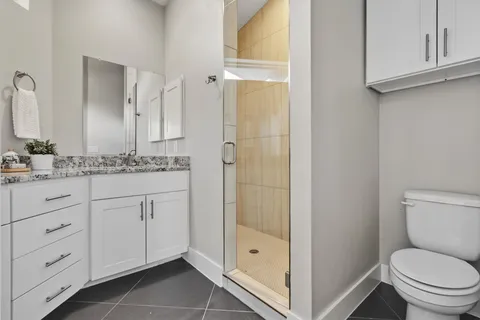 a bathroom with a granite countertop sink toilet mirror and shower