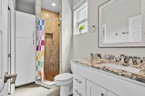 a bathroom with a granite countertop sink toilet and shower