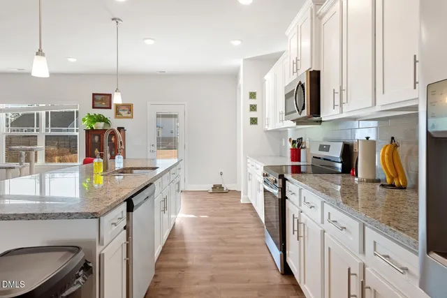 a kitchen with stainless steel appliances granite countertop a sink a stove and a refrigerator