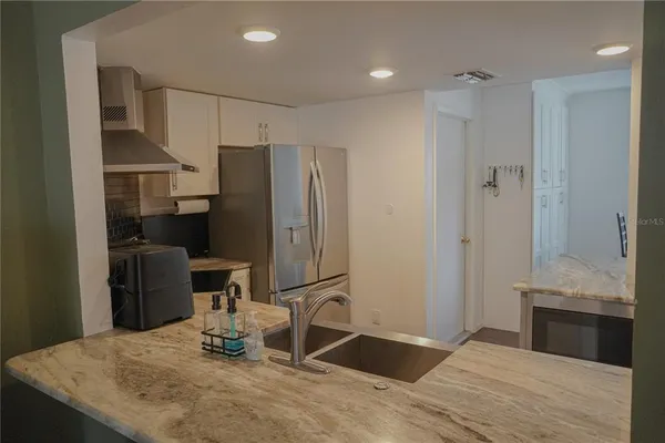 a kitchen with granite countertop a refrigerator and a sink