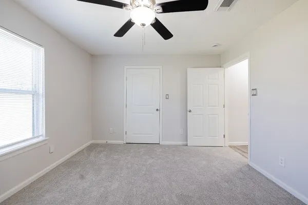 an empty room with a window and a fan